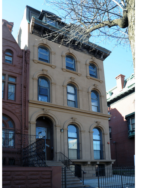 A brown building with a black iron fence in front.