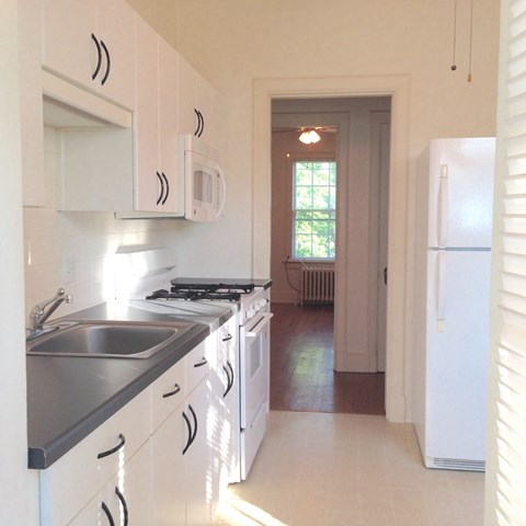 A kitchen with white cabinets and a black counter top.