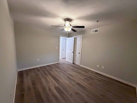 A room with a ceiling fan and wooden flooring.