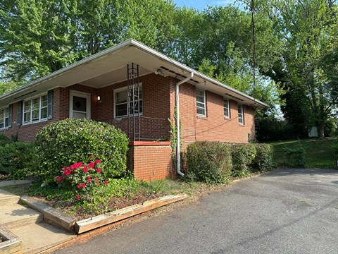 A red brick house with a white roof and a flower bed in front.