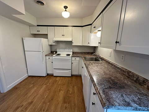 A kitchen with white appliances and cabinets.
