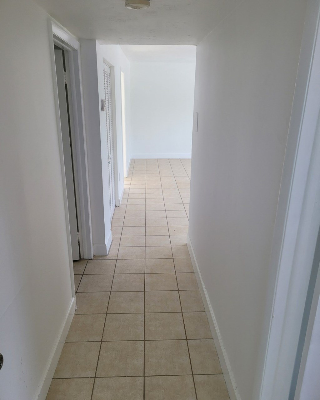 an empty hallway with a tiled floor and white walls