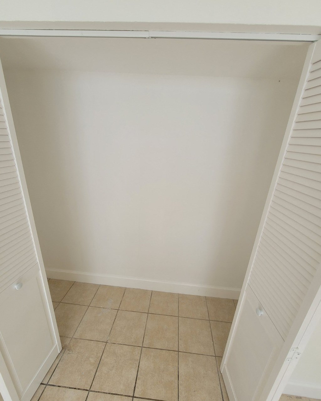 an empty room with a closet and a tiled floor