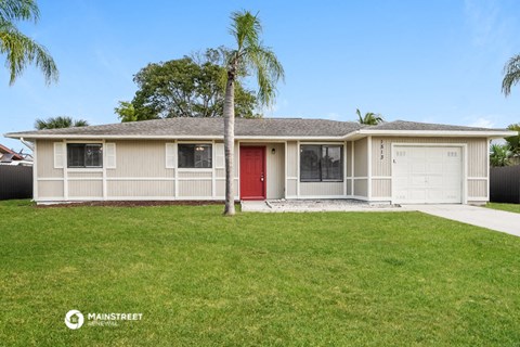 a white house with a palm tree and a red door