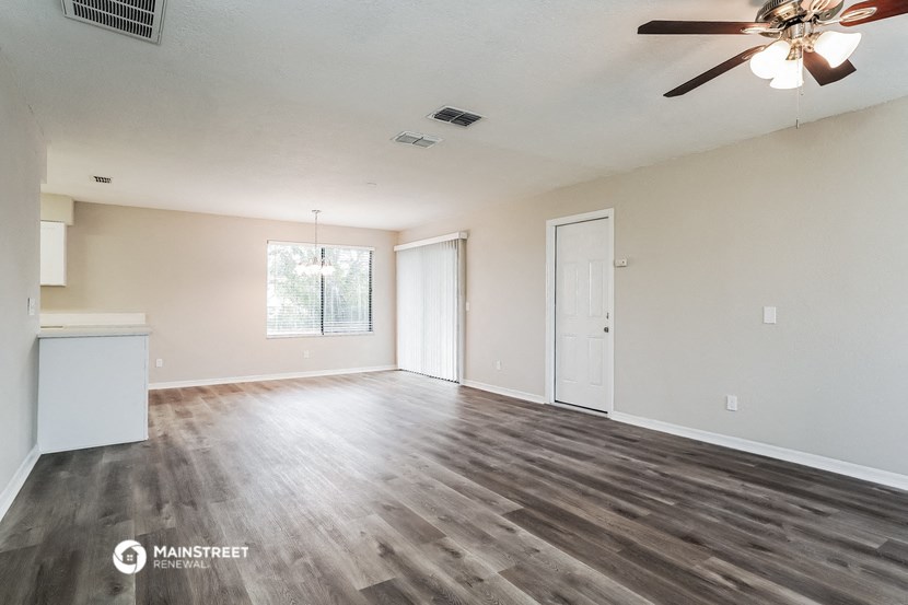 the living room of an empty house with a ceiling fan