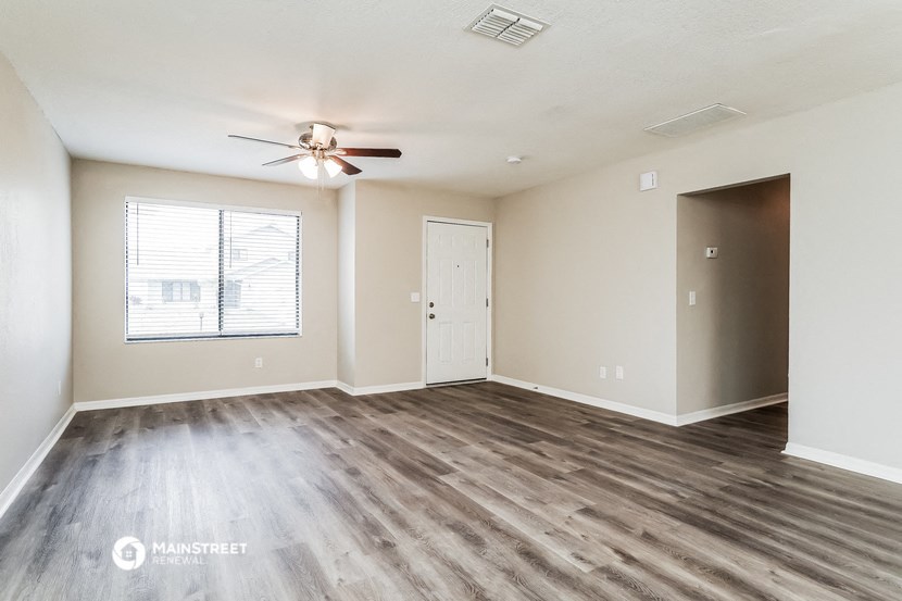 an empty living room with wood flooring and a ceiling fan