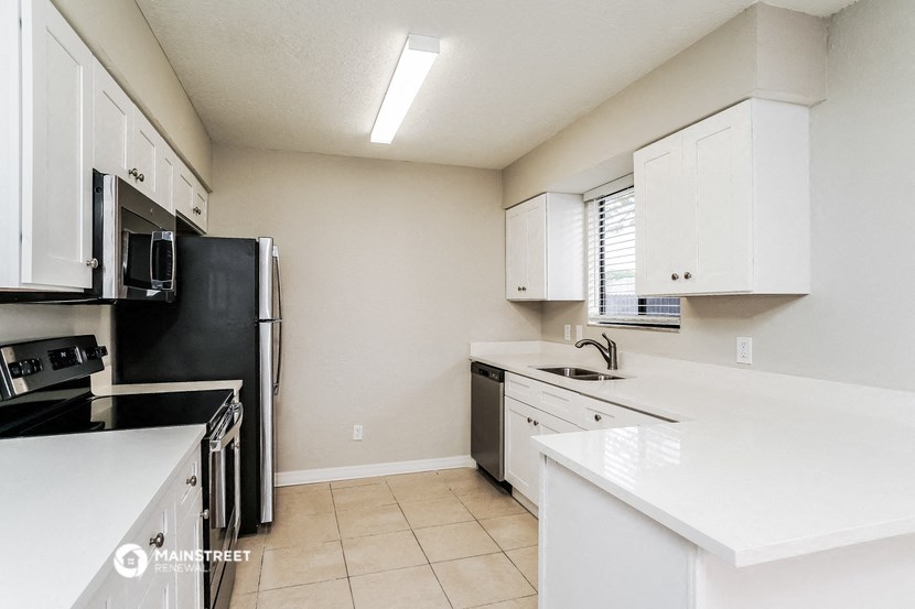a kitchen with white cabinets and black appliances and white counter tops