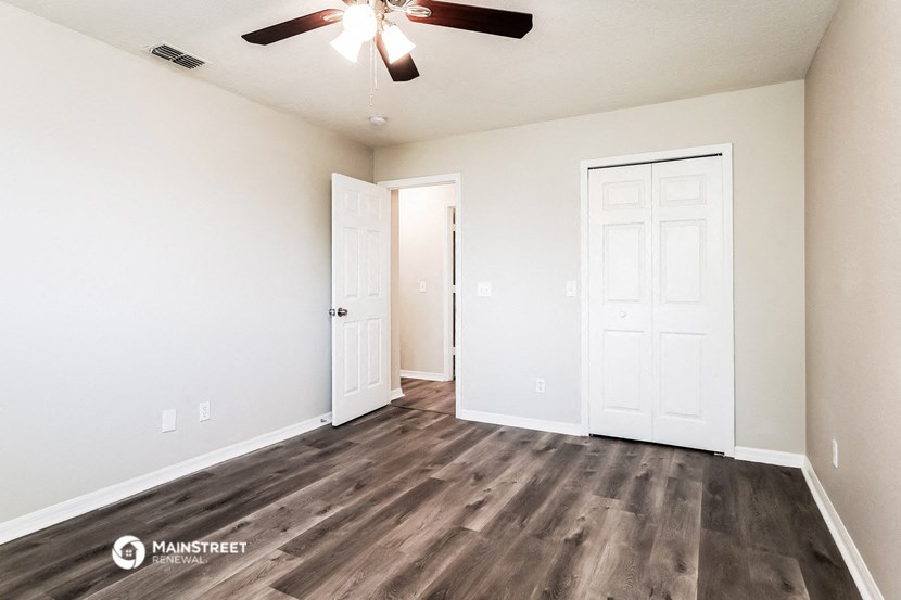 a living room with white walls and a ceiling fan