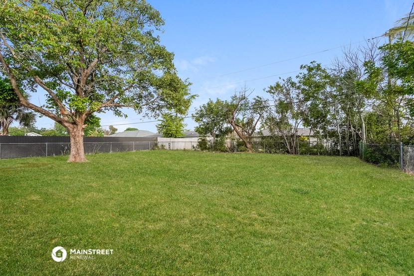 a yard with trees and a fence and a building in the background