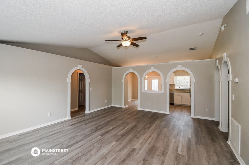 an empty living room with hardwood floors and a ceiling fan