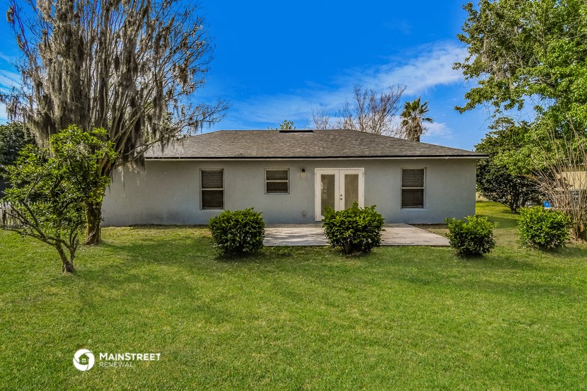 a small white house with a lawn and trees