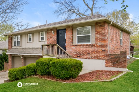 a small brick house with a front porch and a lawn
