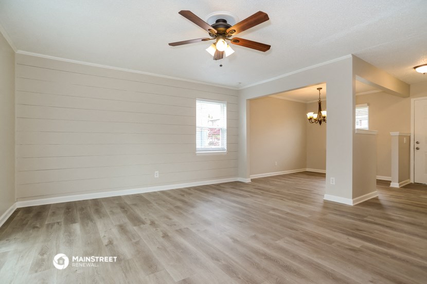 the living room and dining room with white walls and a ceiling fan