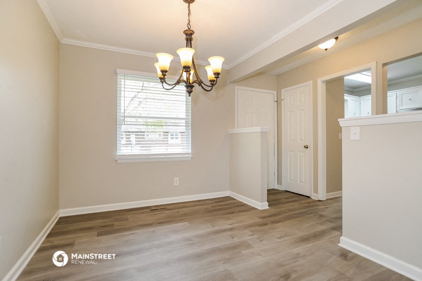 an empty dining room with a chandelier and a window