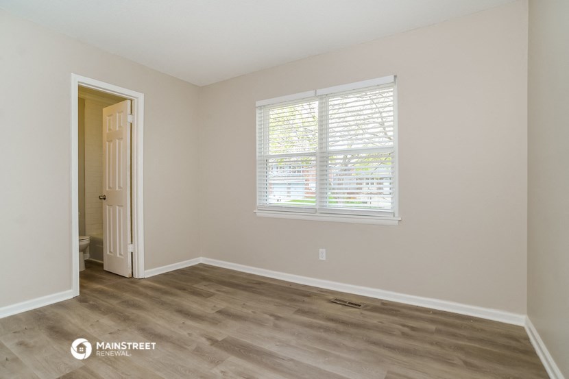 the living room of an empty home with a large window and wood flooring