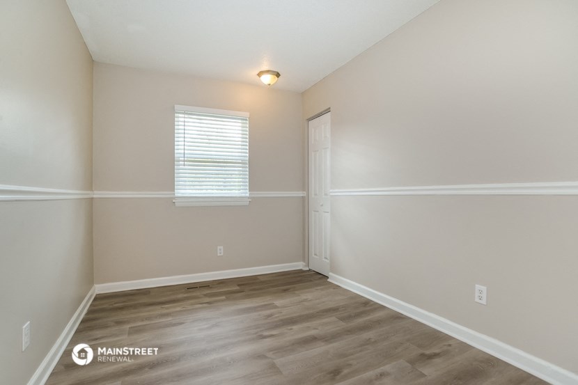 the spacious living room with hardwood flooring and white walls