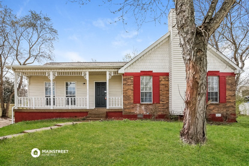 the front of a white house with red doors and a tree