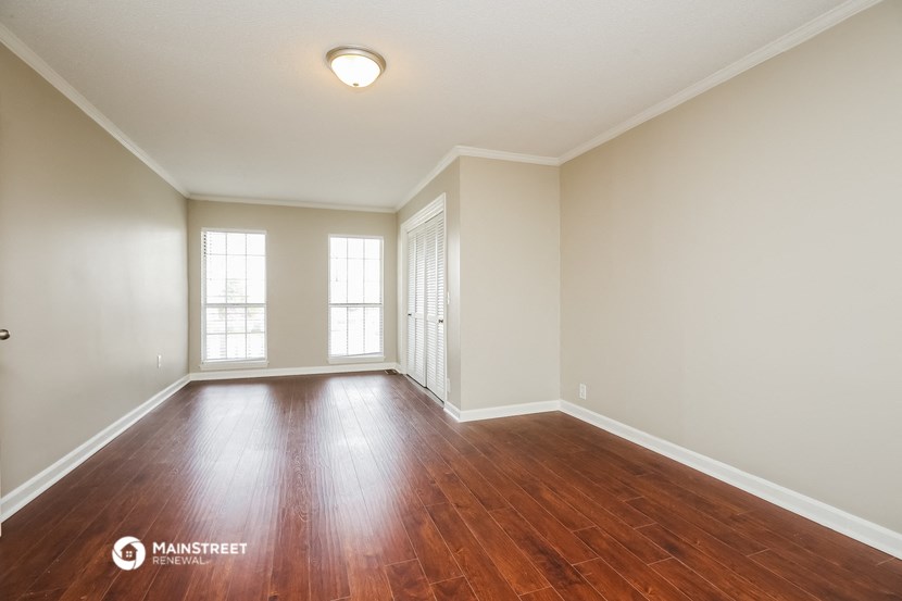 the spacious living room with hardwood flooring and windows