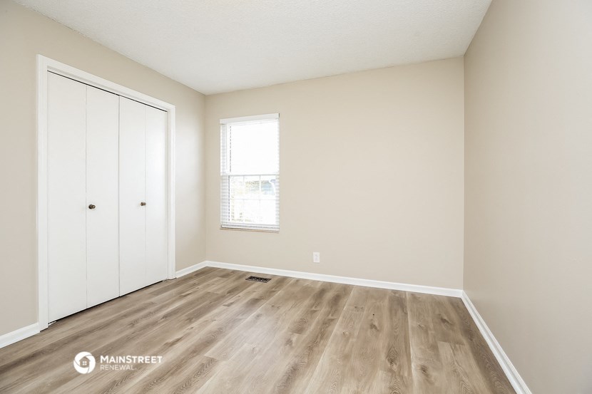 the spacious living room with wood flooring and white walls