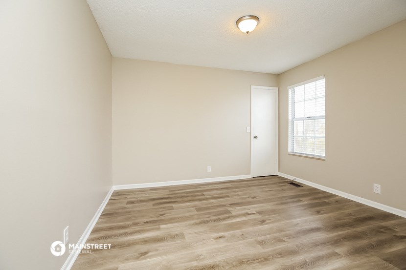 the spacious living room with hardwood flooring and a window