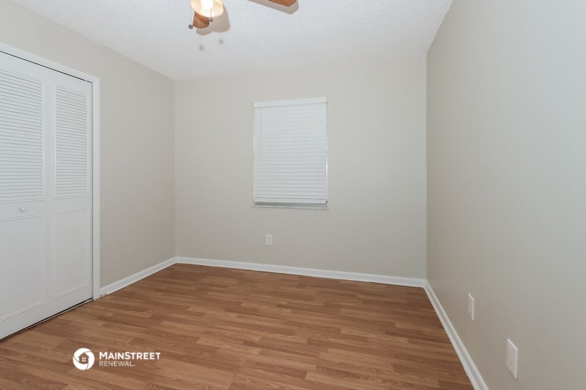 the spacious living room with wood flooring and white walls