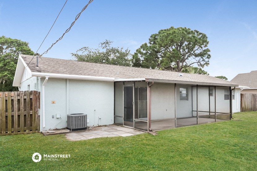a small white house with a patio and a backyard