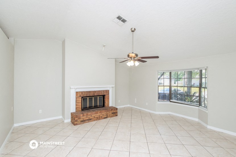 a living room with a fireplace and a ceiling fan