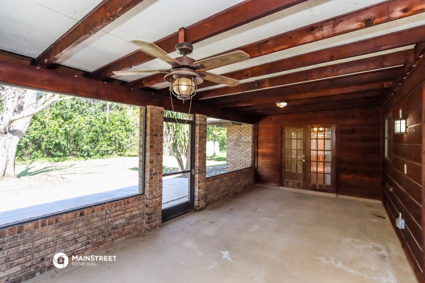 a living room with a ceiling fan and a brick wall