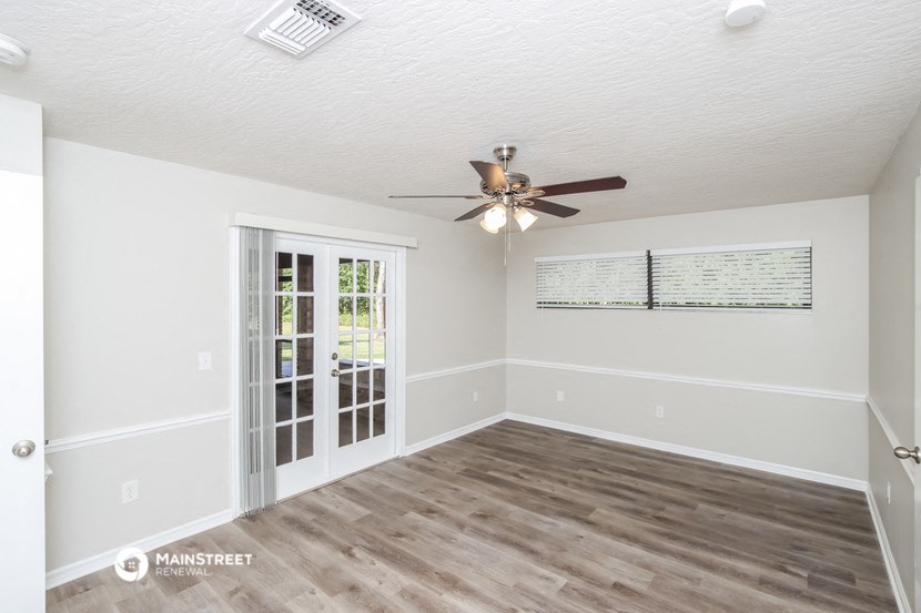 an empty living room with a ceiling fan and a door