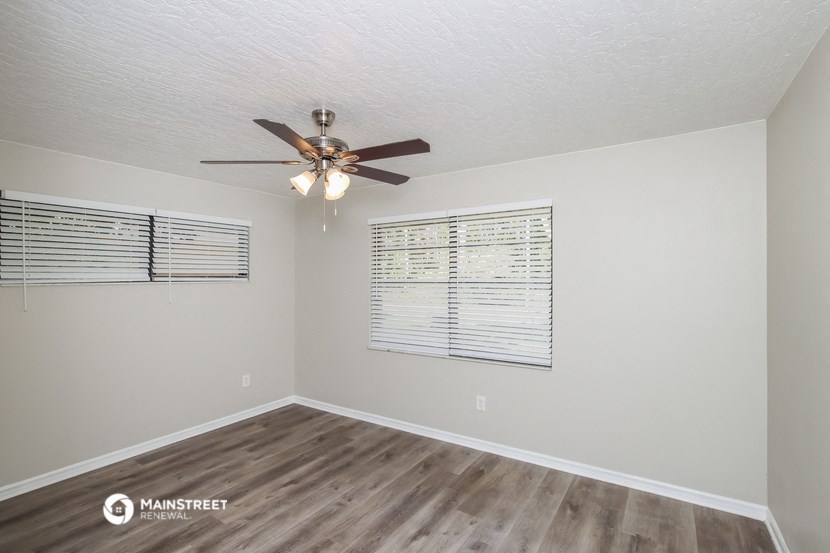 the spacious living room has a ceiling fan and a large window