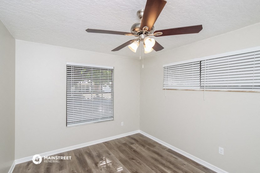 the spacious living room has a ceiling fan and a window