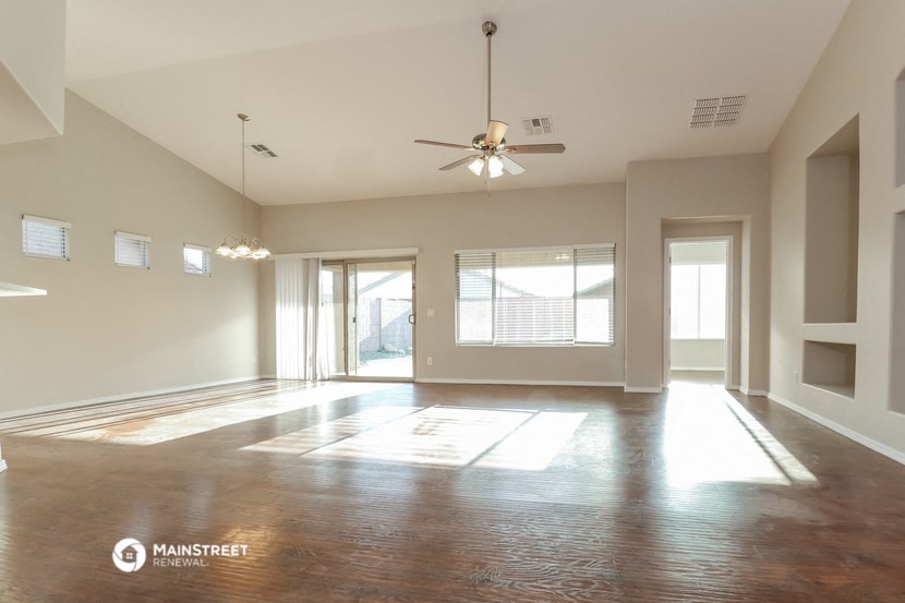 an empty living room with a ceiling fan and a window
