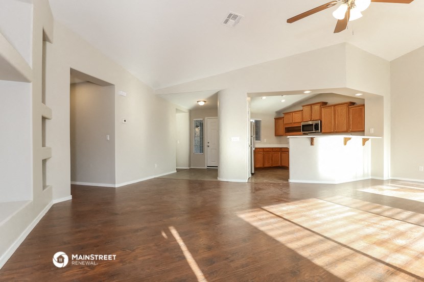 an empty living room and kitchen with a ceiling fan