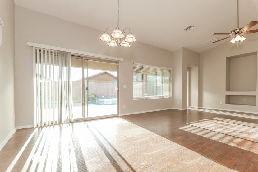 an empty living room with sliding glass doors and a ceiling fan