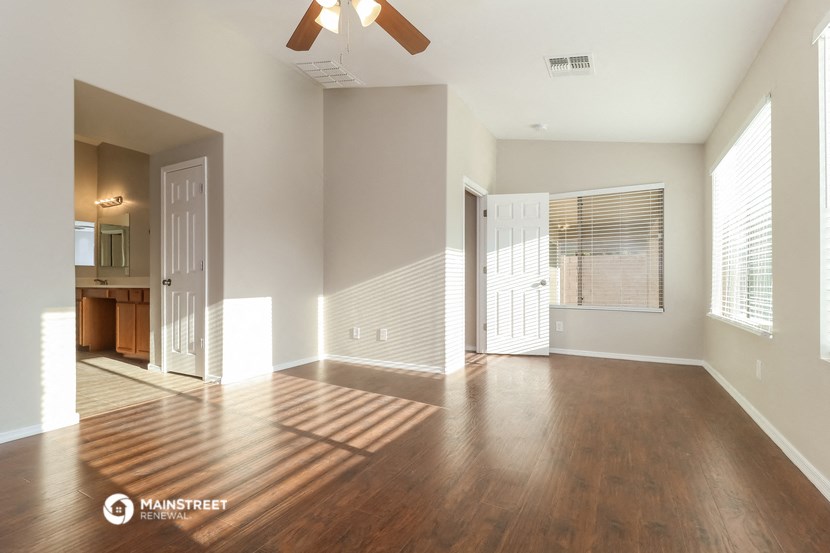 an empty living room with wood floors and a ceiling fan