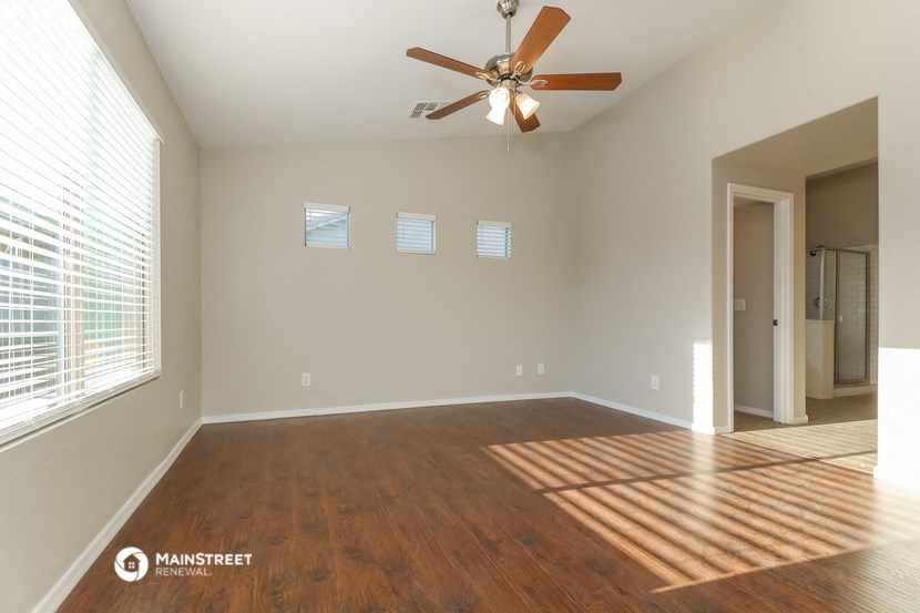 an empty living room with a ceiling fan and a large window
