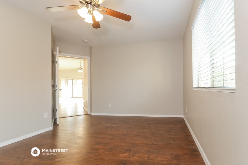an empty living room with wood flooring and a ceiling fan