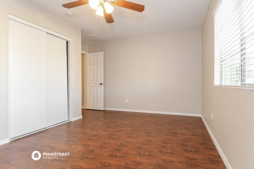 the spacious living room with wood flooring and a ceiling fan