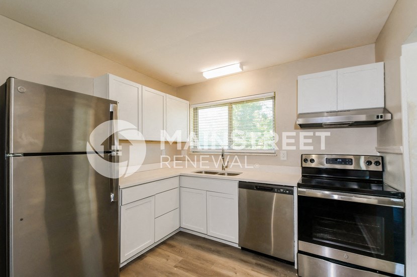 a renovated kitchen with stainless steel appliances and white cabinets