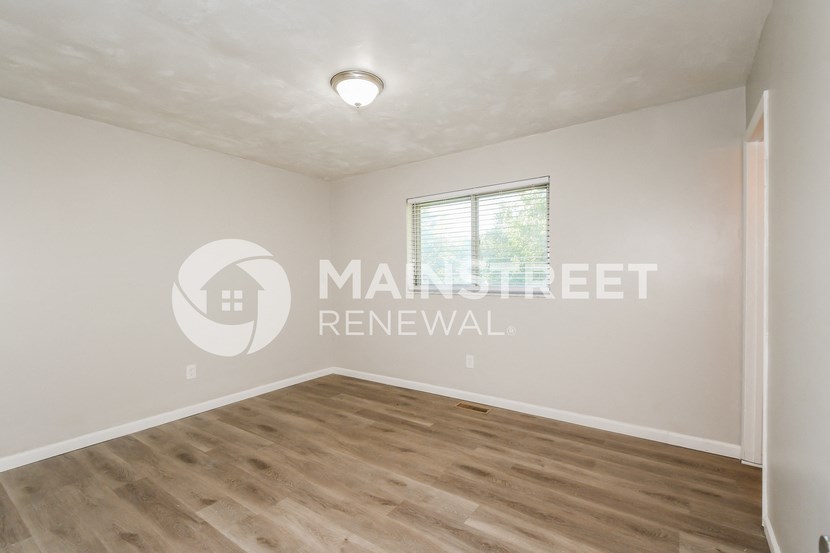 a bedroom with a hardwood floor and a window