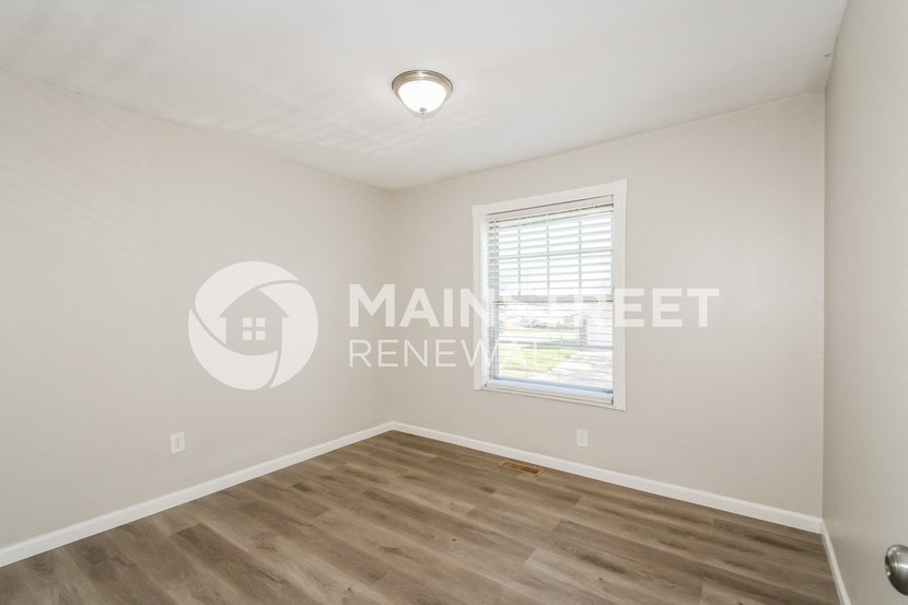 a bedroom with a hardwood floor and a window