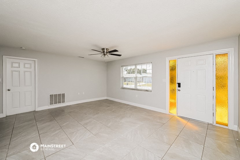 an empty living room with a ceiling fan