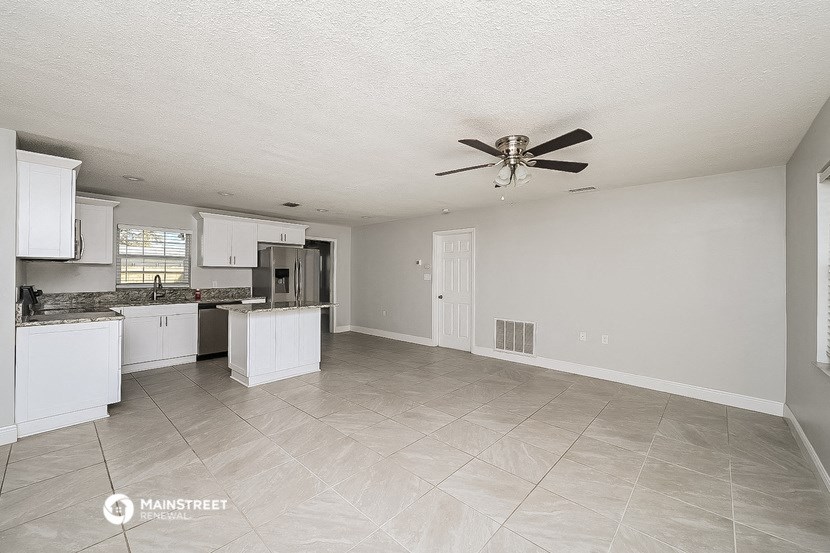 an empty kitchen with a ceiling fan and white cabinets