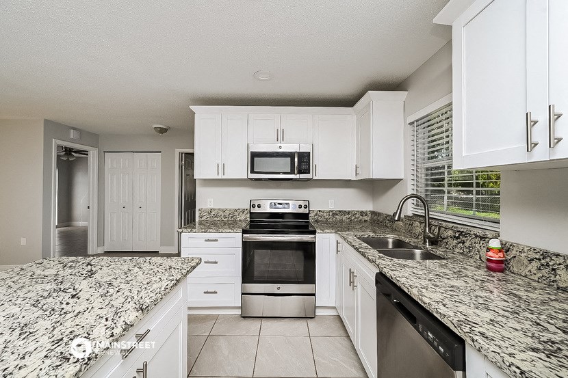 an updated kitchen with granite counter tops and white cabinets