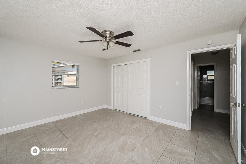 the spacious living room with ceiling fan and tile flooring