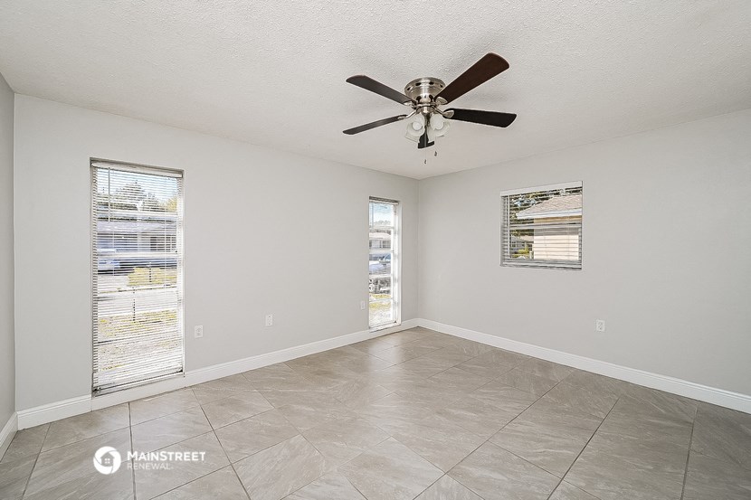 a spacious living room with a ceiling fan and a tiled floor