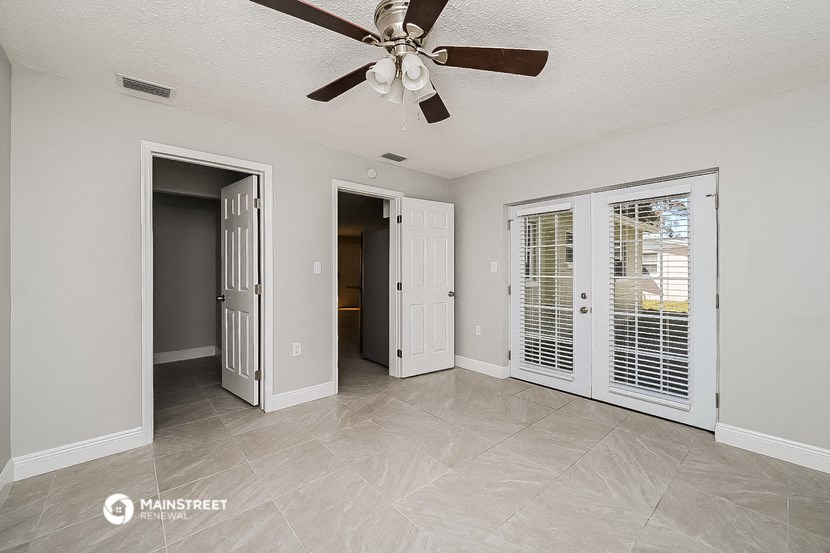 a living room with a ceiling fan and a door to a hallway