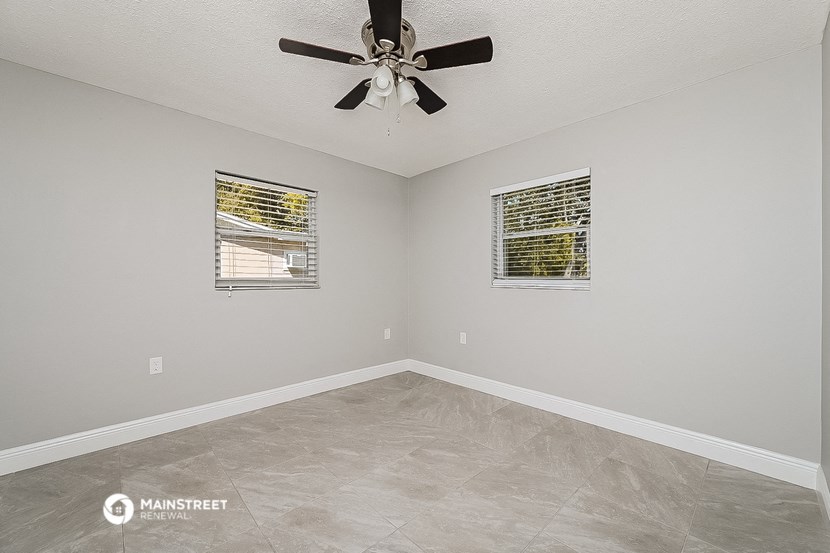 the spacious living room has a ceiling fan and tile flooring