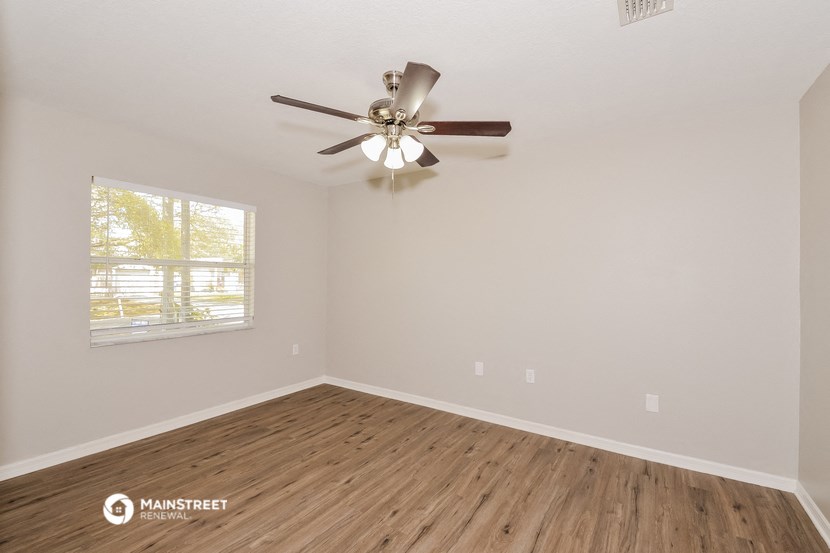 the spacious living room with ceiling fan and wood flooring