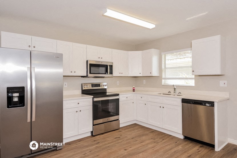 a white kitchen with stainless steel appliances and white cabinets